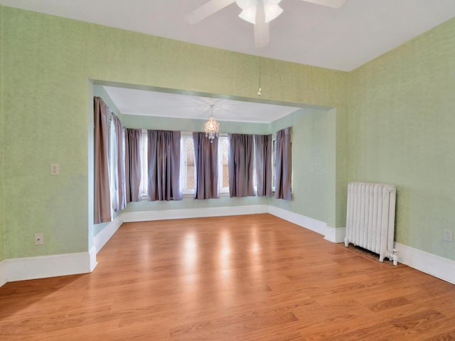 360 1st St, Menasha, WI 54952 - empty room featuring radiator, wood finished floors, a chandelier, a ceiling fan, and baseboards
