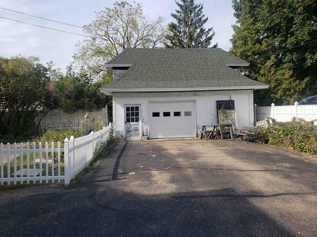 garage featuring driveway and fence