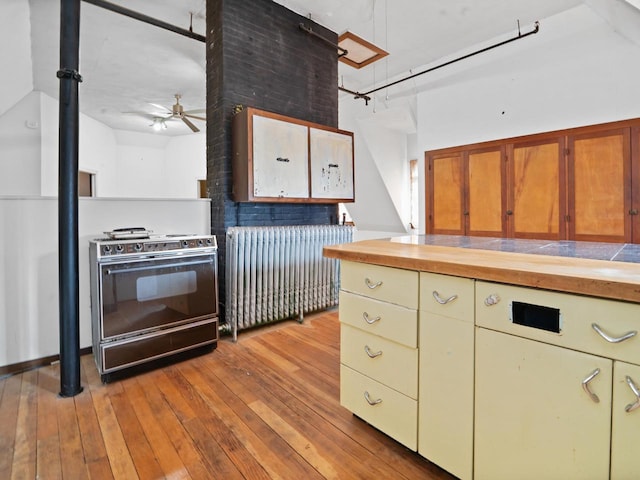 kitchen featuring butcher block countertops, light wood finished floors, a ceiling fan, and black appliances