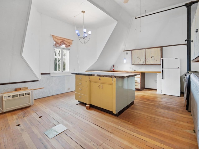kitchen featuring an AC wall unit, a center island, light wood-type flooring, decorative light fixtures, and freestanding refrigerator