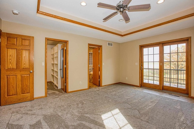 unfurnished bedroom featuring carpet, a raised ceiling, ceiling fan, a spacious closet, and ensuite bathroom