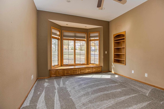 carpeted spare room with ceiling fan and built in features