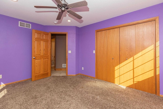 unfurnished bedroom featuring light colored carpet, a closet, and ceiling fan