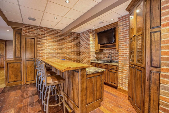 kitchen with brick wall, sink, a kitchen island, and wooden counters