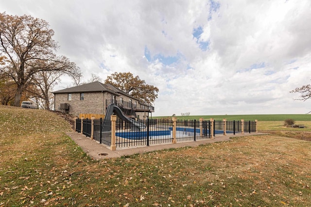 view of swimming pool featuring a water slide, a lawn, and a rural view