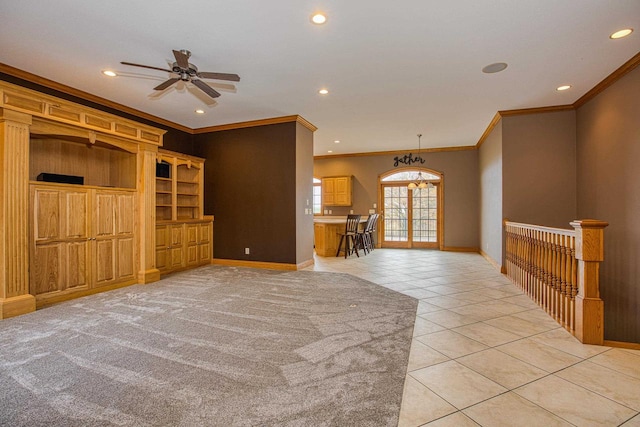 unfurnished living room featuring crown molding, light tile patterned flooring, ceiling fan with notable chandelier, and wood walls