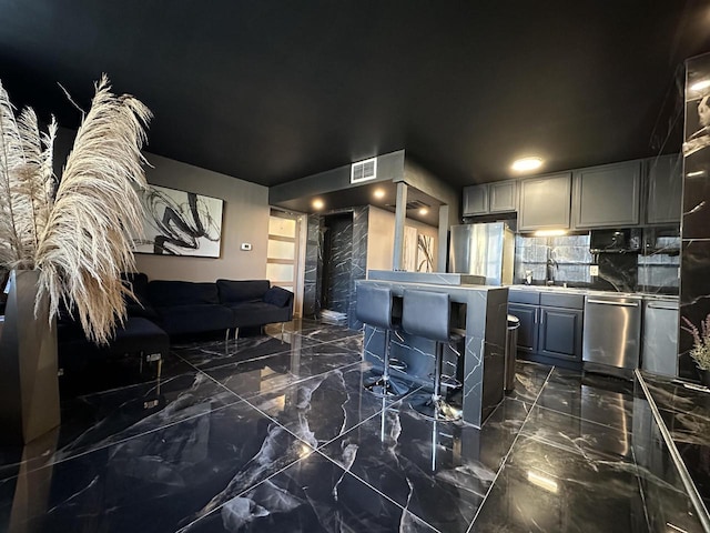 interior space with visible vents, marble finish floor, open floor plan, a sink, and stainless steel appliances