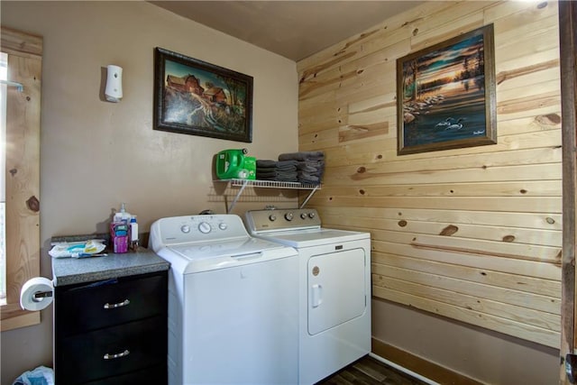 clothes washing area featuring wood walls, dark hardwood / wood-style floors, and washing machine and clothes dryer