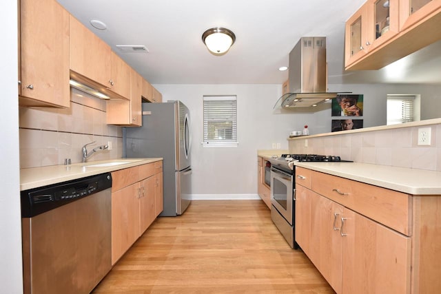 kitchen with island exhaust hood, tasteful backsplash, light wood-type flooring, sink, and stainless steel appliances