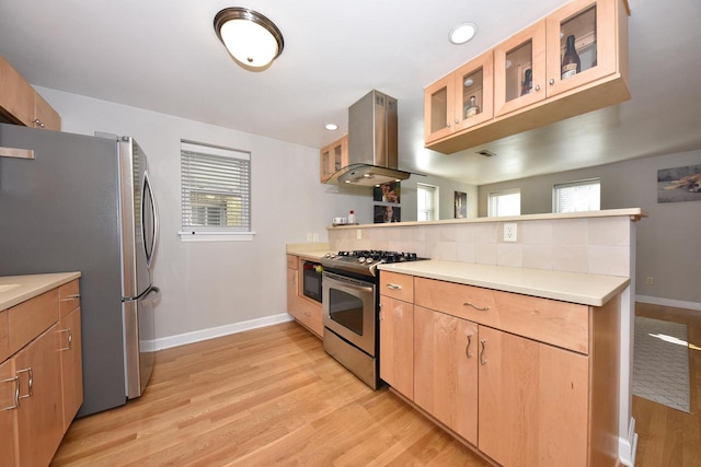 kitchen featuring appliances with stainless steel finishes, island exhaust hood, plenty of natural light, and light wood-type flooring