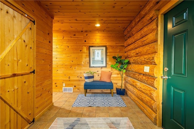 living area featuring log walls, wooden ceiling, light tile patterned flooring, and a barn door