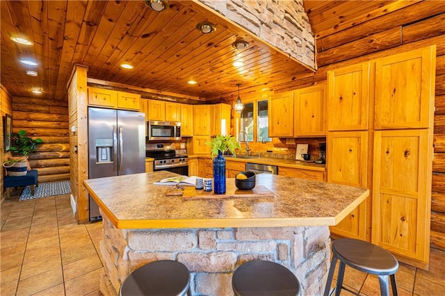 kitchen with a kitchen island, appliances with stainless steel finishes, sink, rustic walls, and decorative light fixtures