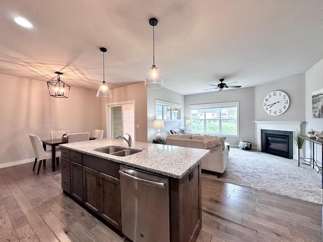 kitchen featuring sink, hanging light fixtures, stainless steel dishwasher, hardwood / wood-style flooring, and a kitchen island with sink