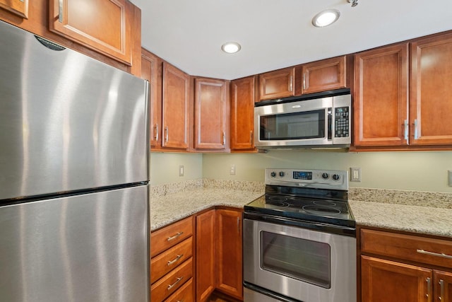 kitchen with light stone counters and appliances with stainless steel finishes