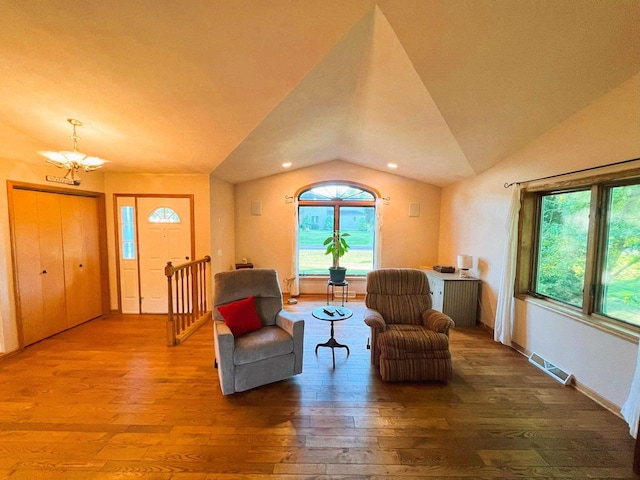 living area featuring lofted ceiling, an inviting chandelier, and hardwood / wood-style floors