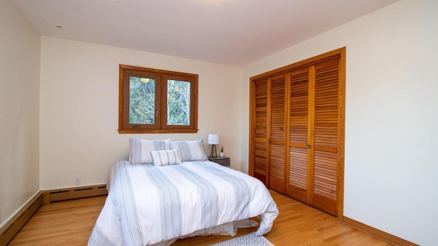 bedroom featuring a closet, a baseboard radiator, and light wood-type flooring