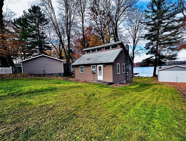 rear view of property with a yard, a water view, and an outdoor structure