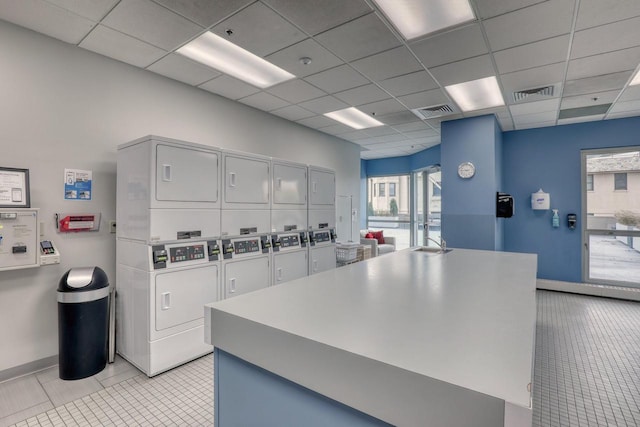 kitchen featuring a drop ceiling, stacked washer and dryer, and light tile patterned floors