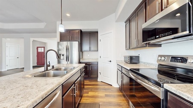 kitchen with hardwood / wood-style floors, hanging light fixtures, appliances with stainless steel finishes, dark brown cabinetry, and sink