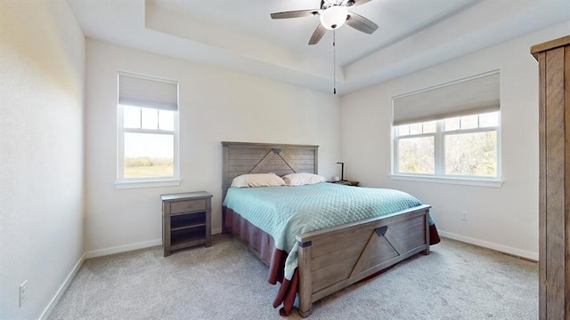 carpeted bedroom featuring a raised ceiling and ceiling fan