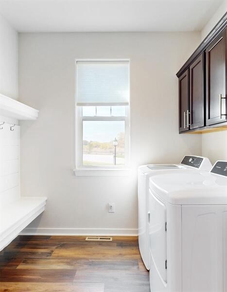 washroom with hardwood / wood-style floors, washing machine and dryer, and cabinets