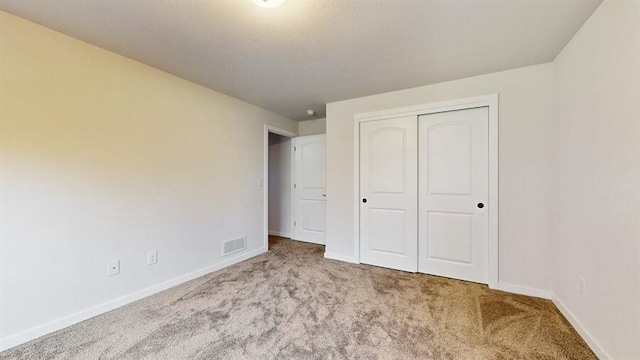 unfurnished bedroom with a closet and light colored carpet