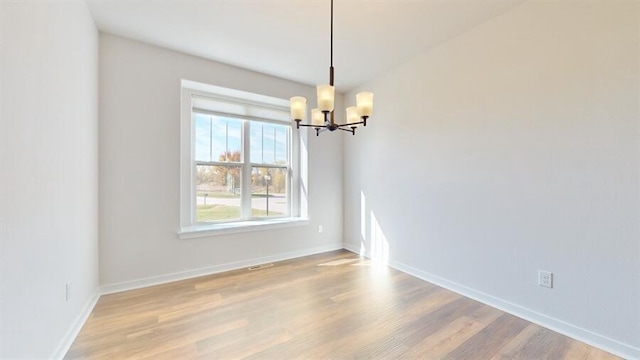 empty room featuring an inviting chandelier and hardwood / wood-style floors