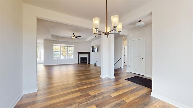 unfurnished living room with ceiling fan with notable chandelier and dark hardwood / wood-style floors