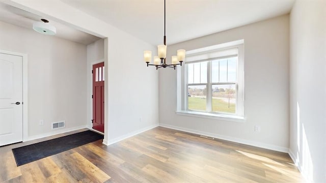 unfurnished dining area featuring hardwood / wood-style flooring and a chandelier