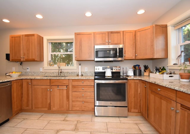 kitchen featuring sink, light stone countertops, and stainless steel appliances