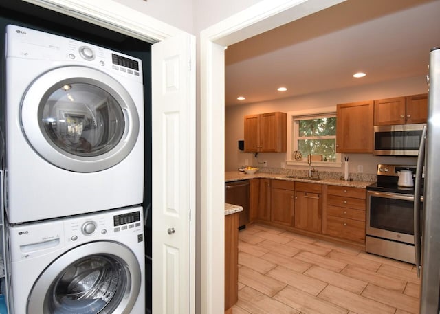 laundry room with sink, stacked washer and dryer, and light wood-type flooring