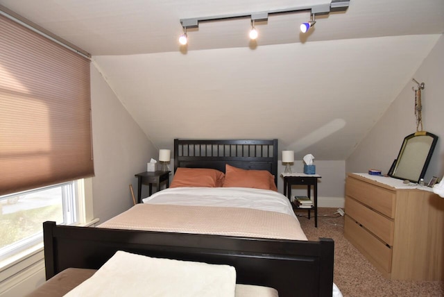 carpeted bedroom featuring lofted ceiling and rail lighting