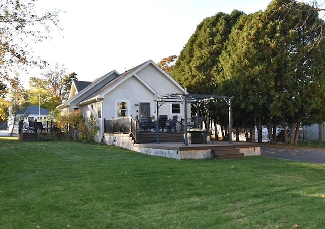 rear view of house featuring a wooden deck, a pergola, and a yard