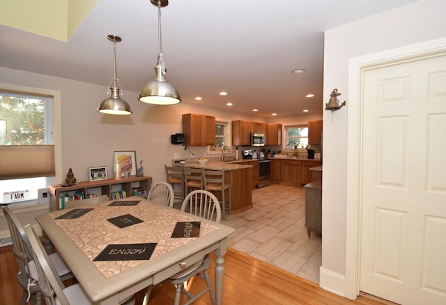 dining room with sink, light hardwood / wood-style flooring, and a wealth of natural light