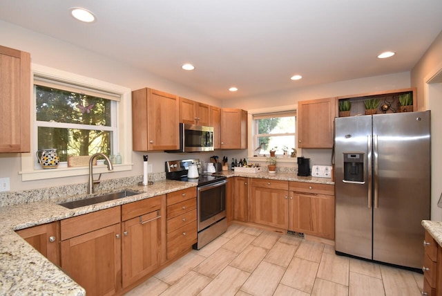 kitchen featuring sink, appliances with stainless steel finishes, and light stone counters