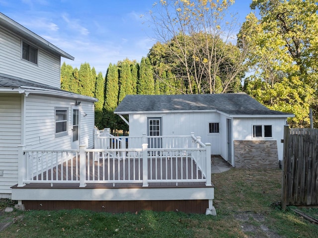 back of property with roof with shingles, fence, a deck, and stone siding