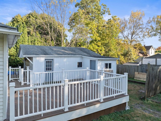 rear view of property featuring roof with shingles, fence, and a wooden deck