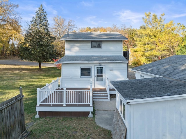 rear view of property featuring fence, a yard, and a deck