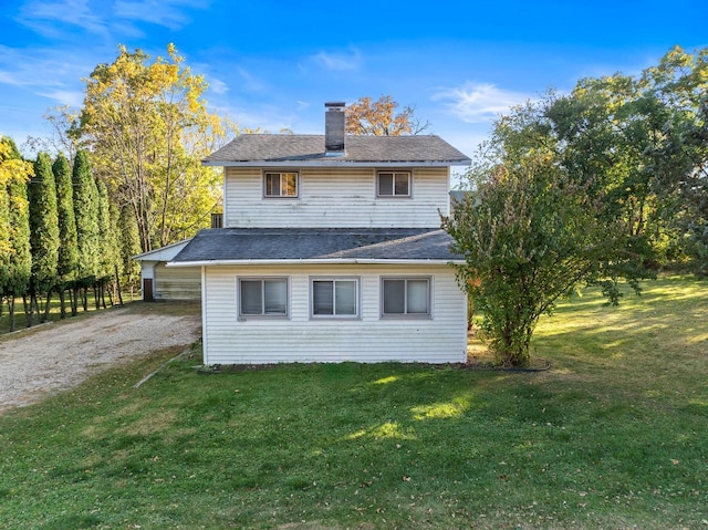 rear view of property with a lawn, driveway, and a chimney