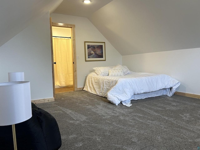 carpeted bedroom with ensuite bath and lofted ceiling