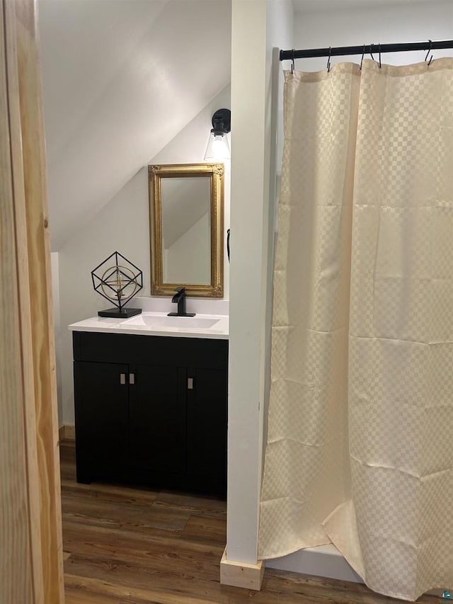 bathroom featuring vanity, walk in shower, vaulted ceiling, and hardwood / wood-style floors