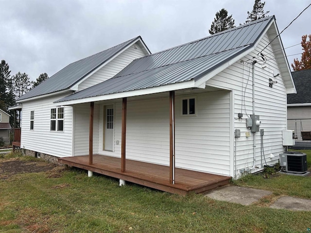 rear view of house featuring a deck, cooling unit, and a lawn