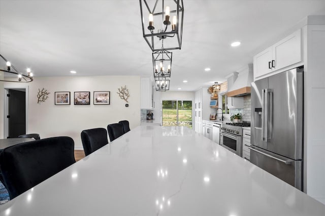 kitchen with white cabinets, decorative light fixtures, and premium appliances