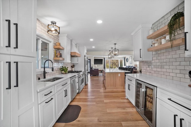 kitchen featuring white cabinetry, sink, beverage cooler, and light wood-type flooring