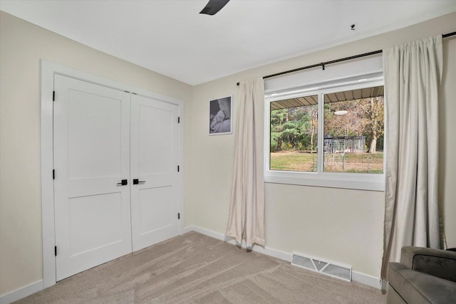 unfurnished bedroom with light carpet, a closet, and ceiling fan