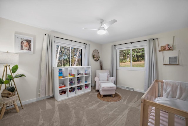 carpeted bedroom with a nursery area and ceiling fan