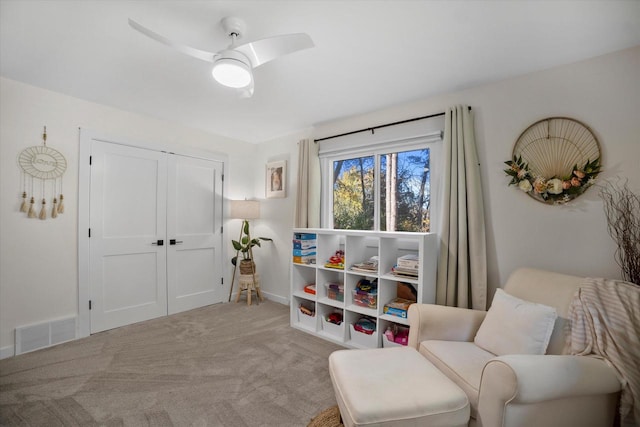 living area with ceiling fan and light colored carpet