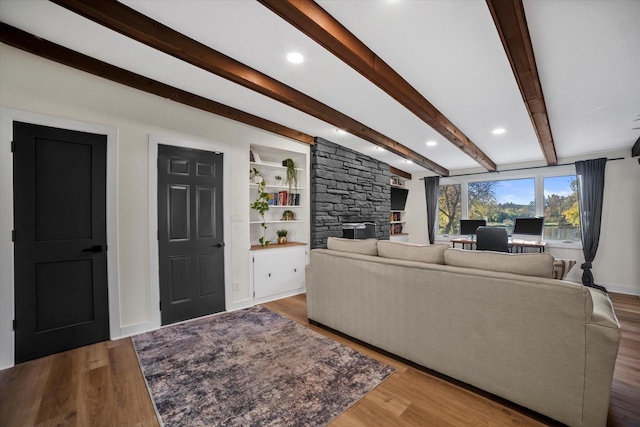 living room with hardwood / wood-style flooring, beamed ceiling, and a fireplace