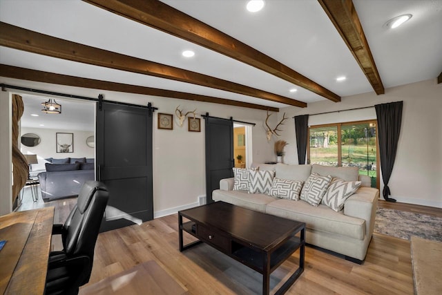 living room with beam ceiling, a barn door, and light wood-type flooring