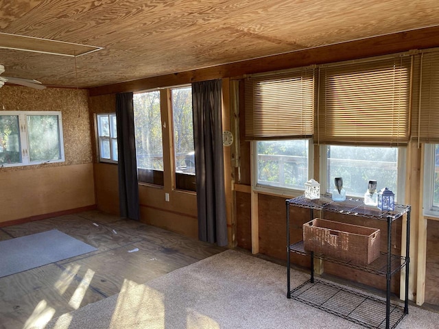 unfurnished sunroom with ceiling fan, a healthy amount of sunlight, and wood ceiling